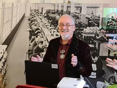 Ein Mann mit Brille präsentiert vor einer großen historischen Aufnahme.