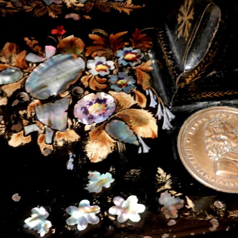 Nahaufnahme einer kunstvoll verzierten Oberfläche mit floralen Motiven und Perlmuttintarsien