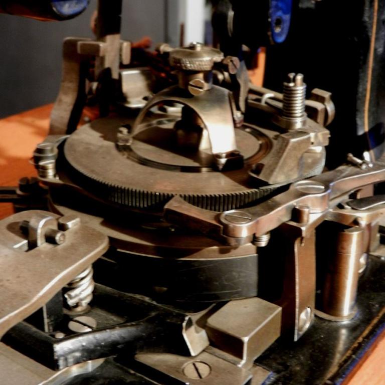 Nahaufnahme eines komplexen, alten mechanischen Geräts mit Zahnrädern und Metallhebeln.