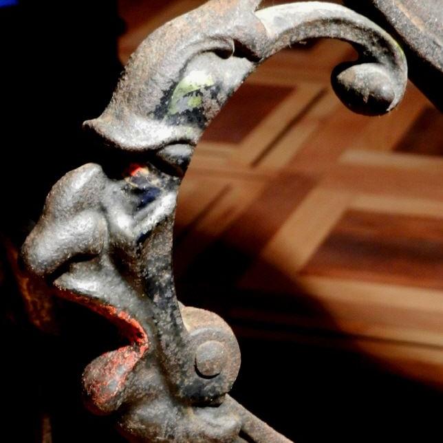Nahaufnahme eines verzierten, antiken Metallgestells mit Fratze
