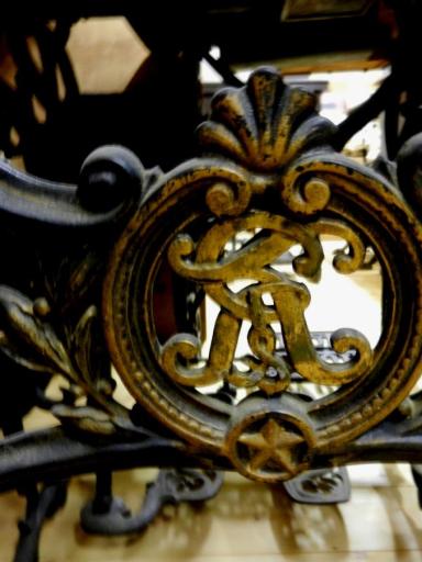 Nahaufnahme eines verzierten Metallgestells mit floralen Motiven.
