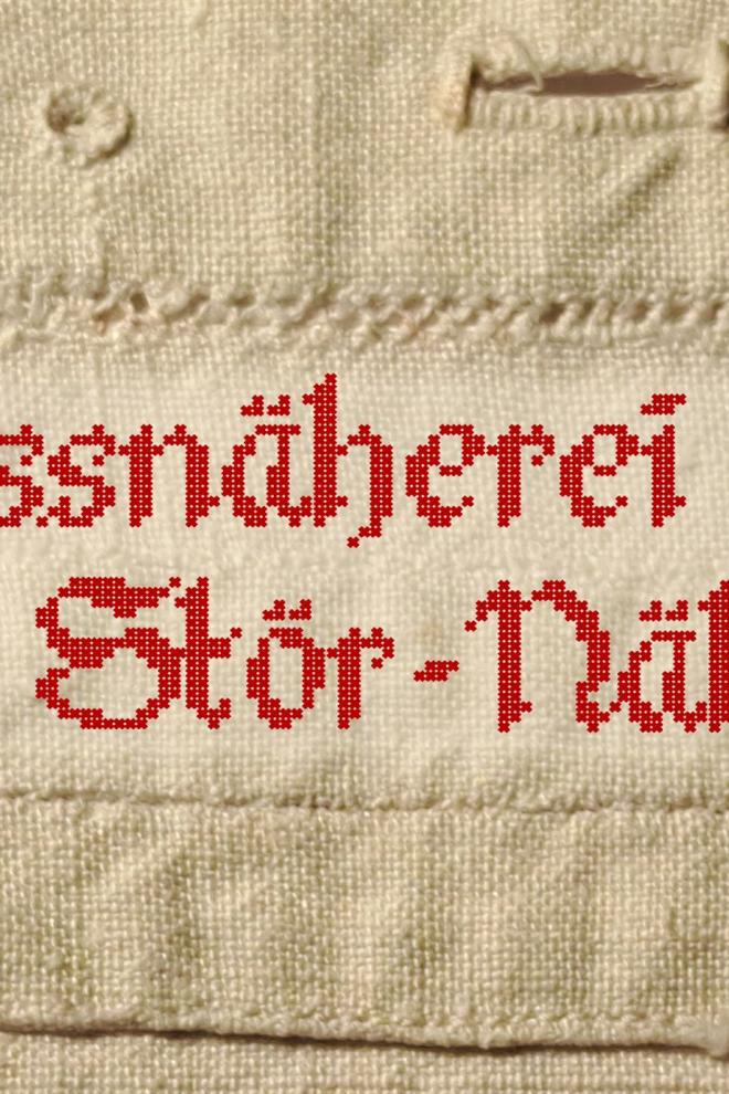Rote Stickereien mit dem Schriftzug Weissnäherei Stör-Näherei auf hellem Stoff.